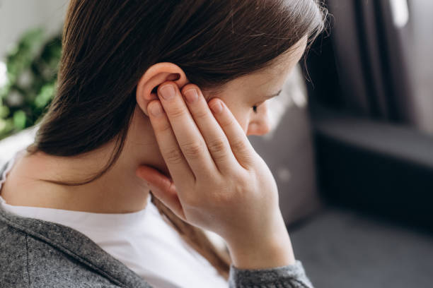 Photo of woman holding her ear from tinnitus, which is a symptom that the SomniBand Sleep Headphones can help fix.